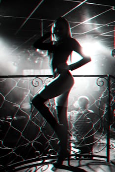 silhouette of a girl dancer go-go dancing posing on stage in a nightclub. Black and white photo with glitch effect and small grain