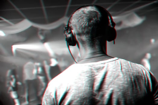 head of a DJ with headphones playing at the event in a nightclub. Black and white photo with glitch effect and small grain