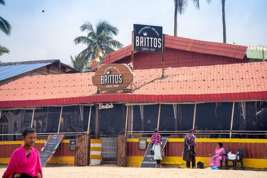 Goa, India - 16th Aug 2024: wide angle shot showing famous bar shack Brittos on baga calangute beach with red tiled roof, people roaming around this popular tourist spot