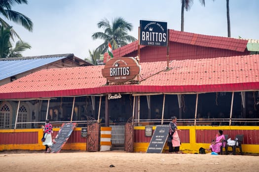 Goa, India - 16th Aug 2024: wide angle shot showing famous bar shack Brittos on baga calangute beach with red tiled roof, people roaming around this popular tourist spot