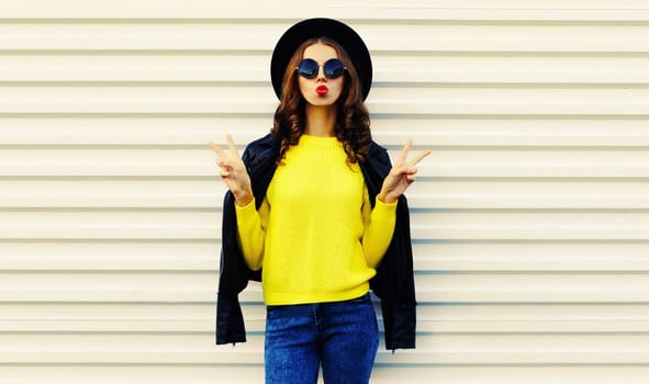 Fashionable stylish young woman posing in black jacket with backpack on white background