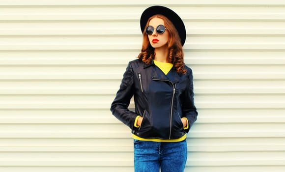 Fashionable portrait of stylish young woman posing in black rock style jacket on white background