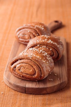 Korvapuusti, traditional finnish cinnamon and cardamom rolls, fresh baked buns on the wooden board, sweet dessert Sweden and Finland, horizontal banner with copy space