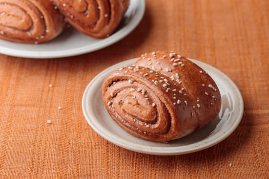 Korvapuusti, traditional finnish cinnamon and cardamom rolls, fresh baked buns on the plate, sweet dessert Sweden and Finland, horizontal banner with copy space