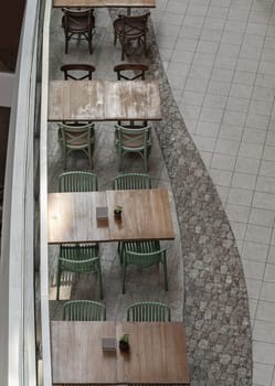Bangkok, Thailand - 28 Sep, 2024 - Looking down at Wooden tables and green chairs. Area in restaurant inside the shopping mall. Space for text, Selective focus.