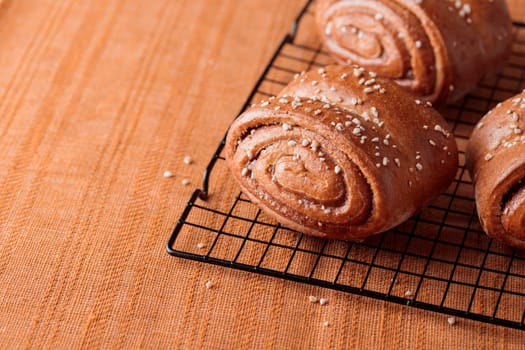 Korvapuusti, traditional finnish cinnamon and cardamom rolls, fresh baked buns on the metal grid, sweet dessert Sweden and Finland, horizontal banner with copy space