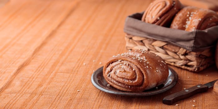 Korvapuusti, traditional finnish cinnamon and cardamom rolls, fresh baked buns on the plate, sweet dessert Sweden and Finland, horizontal banner with copy space