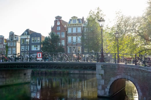 Netherlands. Sunny summer morning on the Amsterdam canal. Lots of bicycles on the bridge and traditional buildings