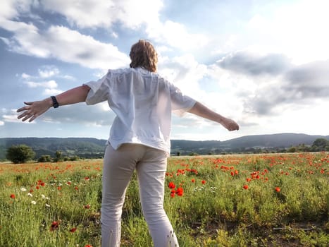 A happy girl in a poppy field. The journey of a middle-aged woman in summer. A tourist on trip
