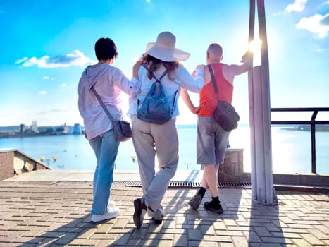 At the waterfront, three friends pose together under the sunlight, appreciating beautiful view and each other's company