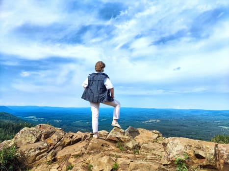 A blogger happily takes a selfie with breathtaking mountain views in the background while enjoying her adventure in nature