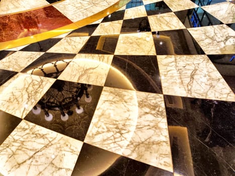A polished marble floor features a striking checkered pattern with warm lighting and reflections.
