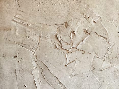 A textured plaster wall showcases intricate patterns and markings, hinting at artistic techniques or natural aging processes.