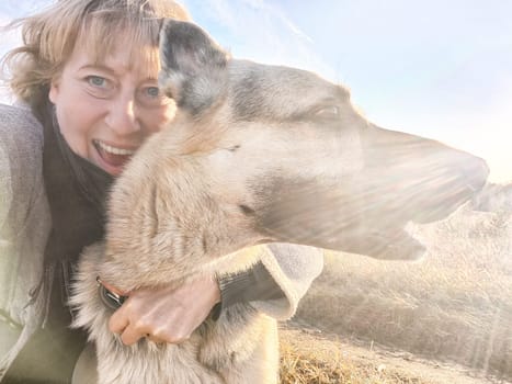 Adult girl or middle aged woman with shepherd dog in an autumn day