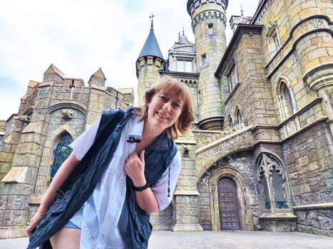A woman enjoys her travel adventure at Garibaldi Castle, showcasing her excitement in a historic setting. The adventures of a middle-aged female tourist on a trip