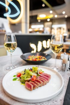 Tuna tataki salad with lettuce, cherry tomatoes and avocado on a marble table in a restaurant. High quality photo