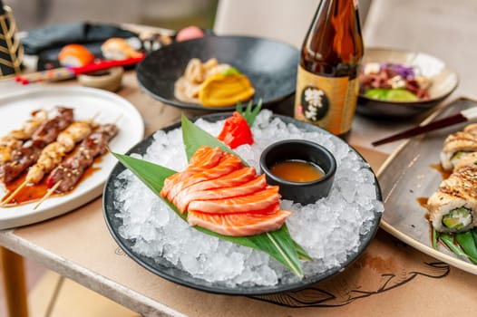 Salmon sashimi plate with sauce and ice on a table in a restaurant