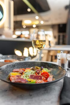 Tuna tataki salad with lettuce, tomatoes and orange on a marble table in a restaurant. High quality photo