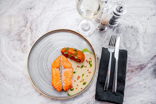 Salmon fillet in cream sauce with herbs on a marble table in a restaurant. High quality photo