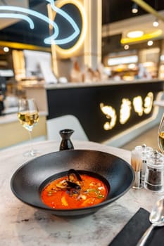 Classic tom yum in a black plate on a table in a restaurant