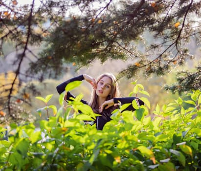 Beautiful girl in green foliage in the autumn park