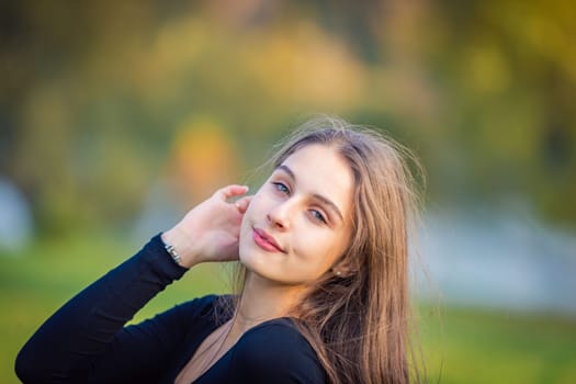 A beautiful girl poses while standing by a pond in an autumn park