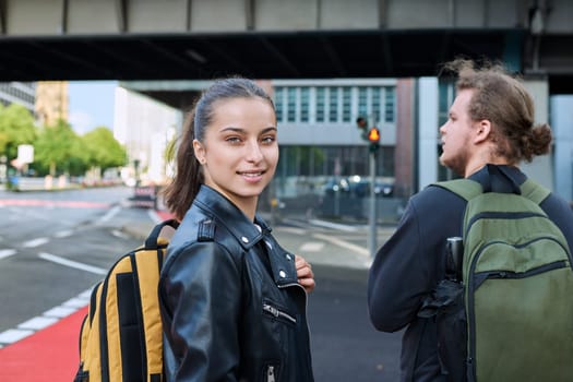 Portrait of teenage high school student, smiling confident girl 16, 17 years old with backpack looking at camera outdoor, on street of modern city. Urban life, adolescence, education, youth concept