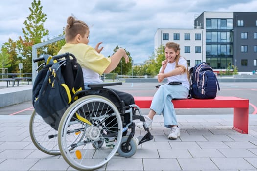 Friendship communication of children of boy in wheelchair and girl. Classmates sitting talking after school lessons. Education, disability, inclusiveness concept