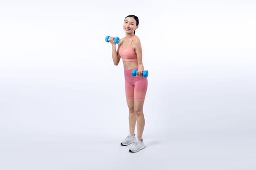 Vigorous energetic woman doing dumbbell weight lifting exercise on isolated background. Young athletic asian woman strength and endurance training session as body workout routine.