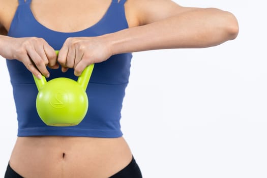 Vigorous energetic woman doing kettlebell weight lifting exercise on isolated background. Young athletic asian woman strength and endurance training session as body workout routine.