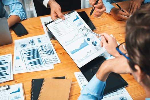 Diverse group of business analyst team analyzing financial data report paper on office table. Chart and graph dashboard by business intelligence analysis for strategic marketing planning Habiliment