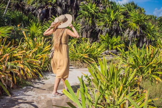 Woman in a hat walks through a tropical park.
