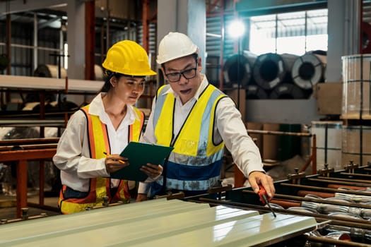 Factory engineer manager collaborate with coworker to conduct quality control on metal sheet product and inspect heavy industrial steel stamping or forming machine. Exemplifying