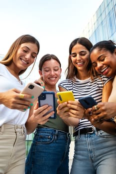 Vertical portrait of happy multiracial group of young women friends looking at mobile phone.Youth lifestyle and social media concept.