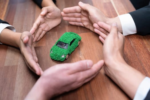 Business people holding EV car model as business synergy partnership unite and take action to utilized eco-transportation to reduce CO2 emission for sustainable and greener future. Quaint