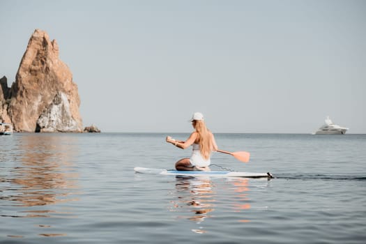 Close up shot of beautiful young caucasian woman with black hair and freckles looking at camera and smiling. Cute woman portrait in a pink bikini posing on a volcanic rock high above the sea