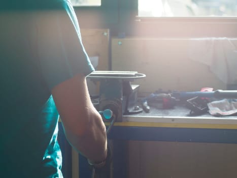Skilled mechanic fixing car part in sunlit garage workshop with precision and concentration. Showcasing expertise and craftsmanship in dirty industrial workplace