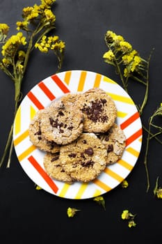 Oatmeal cookies with chocolate on a plate with bright yellow flowers