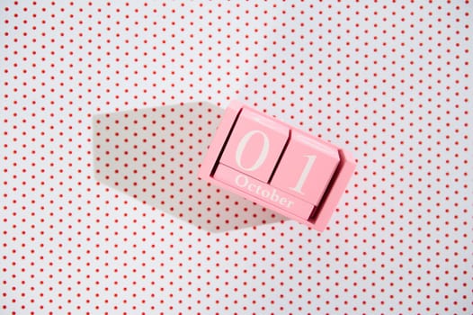 A pink block calendar displaying October 1st on a white polka dot background, creating a playful and modern aesthetic. Ideal for autumn or event imagery.