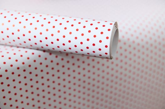 Close-up of red polka dot wrapping paper, showing a seamless pattern perfect for gift packaging and crafting.