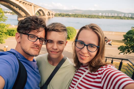 Happy family taking a photo on the Yenisei River background at beauty sunny summer day in Krasnoyarsk city.