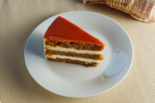 Delicious layers of carrot cake with creamy frosting served on a white plate in a cozy dining setting