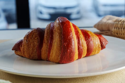 Golden brown croissant sits invitingly on a plate beside a textured linen napkin in a cozy setting