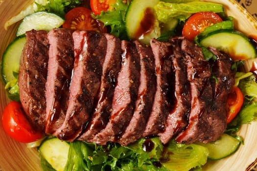 A vibrant platter of grilled steak resting on fresh greens and garden vegetables, artfully arranged and ready to savor