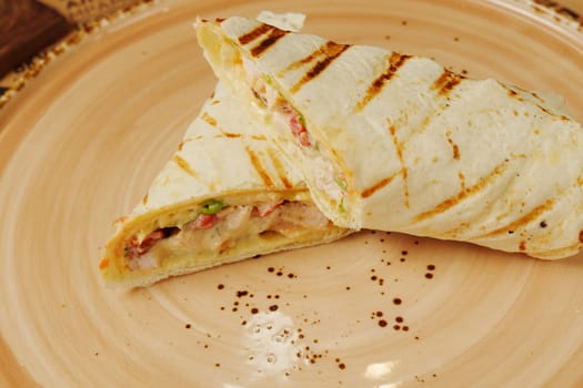 A delicious and hearty wrap filled with succulent beef, fresh veggies, and zesty sauces served on a rustic wooden plate