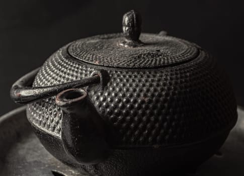 Bangkok, Thailand - 17 Sep, 2024 - Close-up of Black cast iron kettle or teapot on dark background. Light and Shadow, Space for text, Selective Focus.