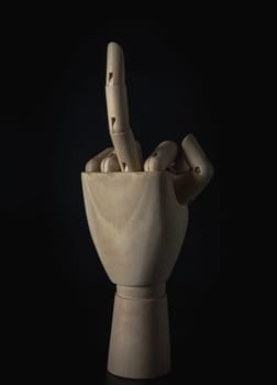 Wooden hand of mannequins with raised middle finger up on dark background. Concept of rude hand sign or hand gesture, Wooden hand puppet, Showing, Symbol, Banner design, Space for text, Selective focus.
