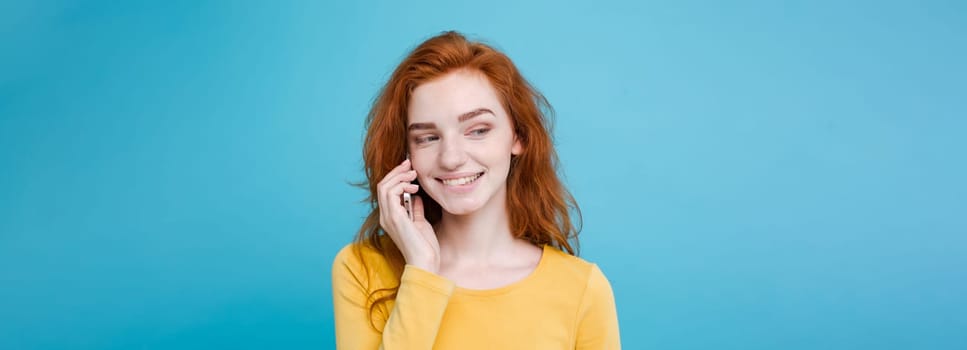 Lifestyle and Technology concept - Portrait of cheerful happy ginger red hair girl with joyful and exciting talking with friend by mobile phone. Isolated on Blue Pastel Background. Copy space.