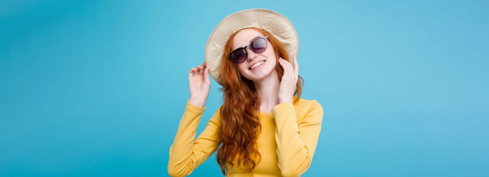 Travel concept - Close up Portrait young beautiful attractive redhair girl wtih trendy hat and sunglass smiling. Blue Pastel Background. Copy space.