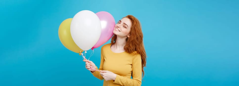 Close up Portrait happy young beautiful attractive redhair girl smiling with colorful party balloon. Blue Pastel Background.